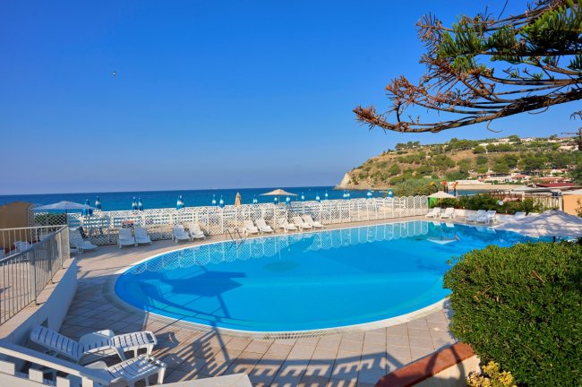 Piscina circolare con vista mare e lettini.