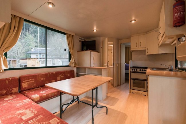 Interno di una casa mobile, con mobili in legno e divano rosso.