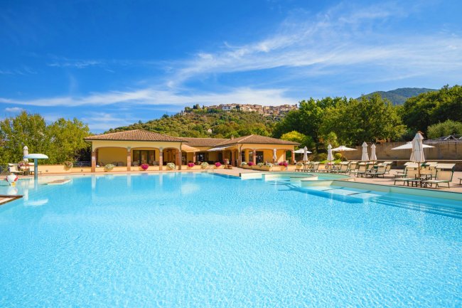 Piscina all'aperto con lettini e ombrelloni.