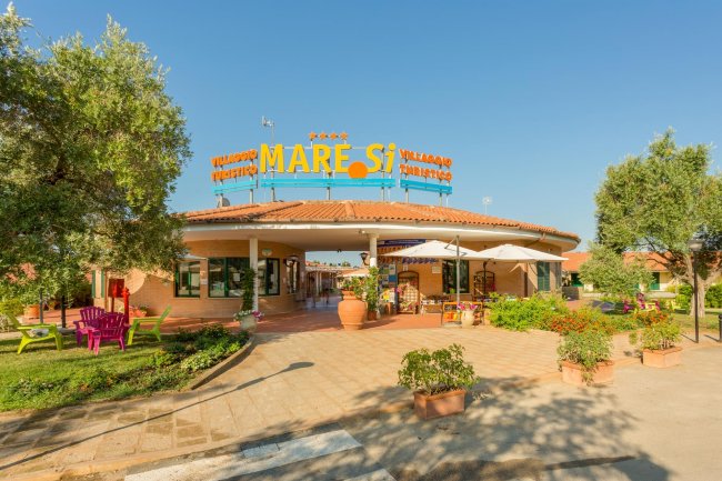 Ingresso di un villaggio turistico con piante.