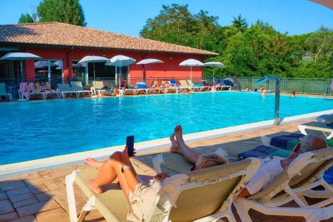 Piscina con lettini e ombrelloni bianchi.