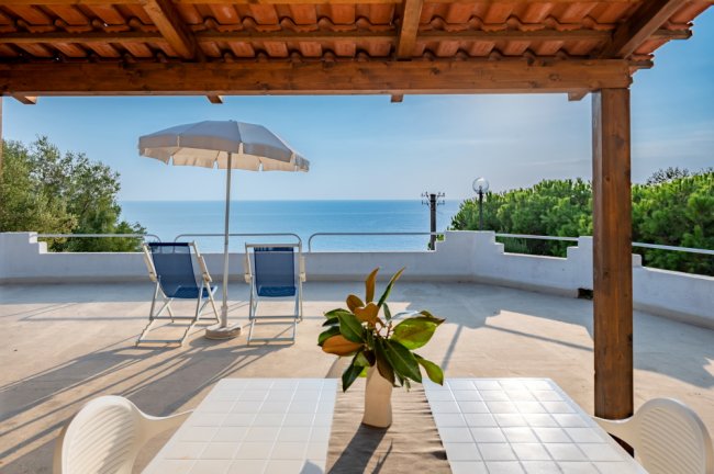 Terrazza con ombrellone, sedie e vista mare.