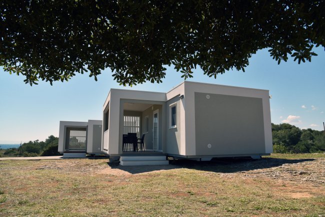 Case prefabbricate bianche su terreno erboso.