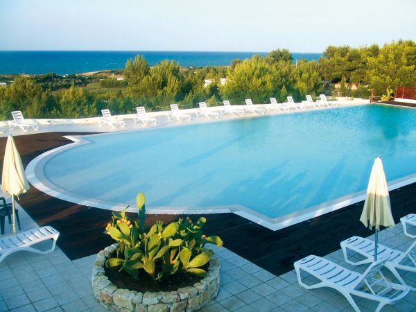 Piscina con lettini bianchi e vista mare.