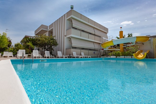 Piscina con scivolo giallo e sdraio.
