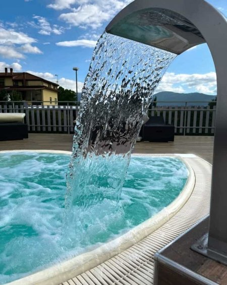 Cascata d'acqua in piscina con cielo azzurro.