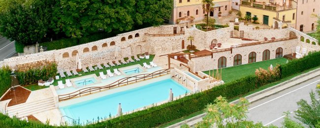 Piscina all'aperto contornata da edifici in pietra.