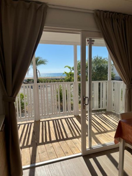Vista da veranda con tende su giardino e mare.
