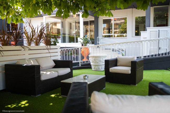 Divanetti e tavolino su prato verde in un giardino.