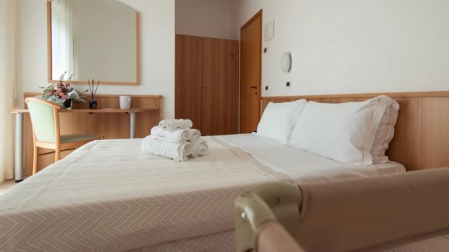 Camera con letto matrimoniale, specchio e scrivania.