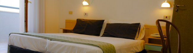 Camera con letto matrimoniale e lampade accese.