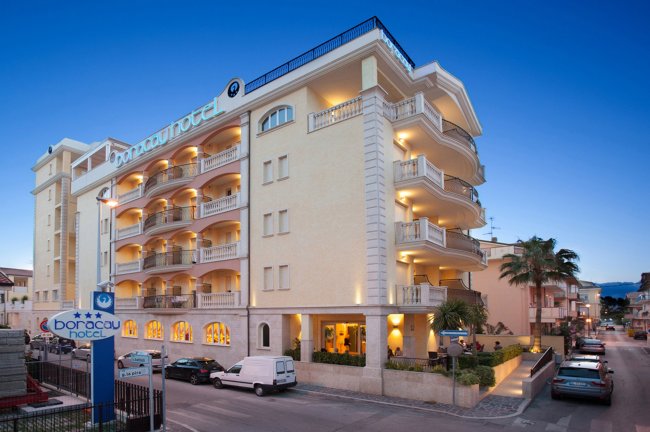 Facciata di un grande hotel con balconi e insegna blu.
