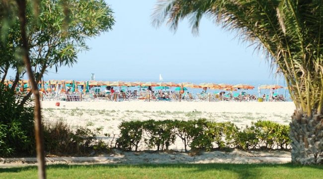 Spiaggia con ombrelloni colorati e mare azzurro.