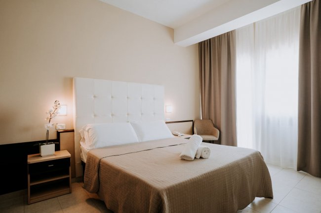 Camera d'albergo con letto matrimoniale e tende.