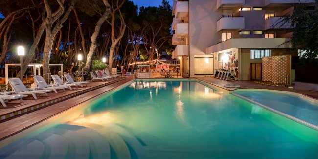 Piscina illuminata di notte vicino a un edificio.