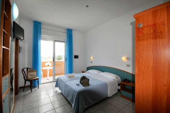 Camera d'hotel con letto matrimoniale e balcone.