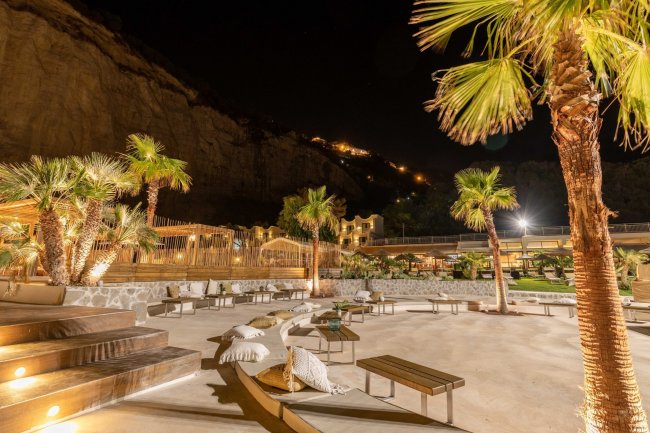 Giardino notturno con palme illuminate.