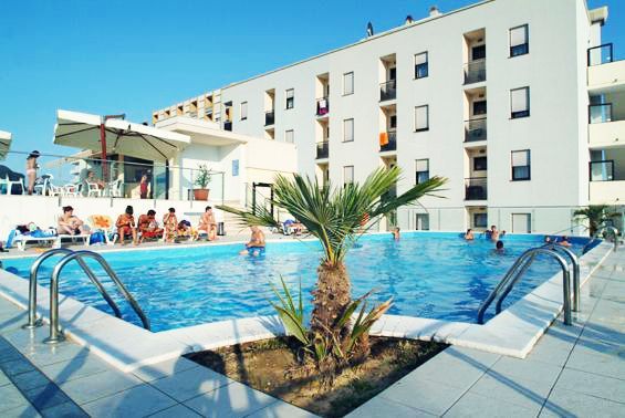 Piscina all'aperto circondata da persone e hotel moderno.