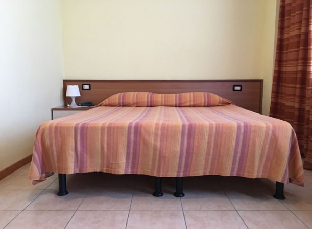 Letto matrimoniale con copriletto arancione a strisce.