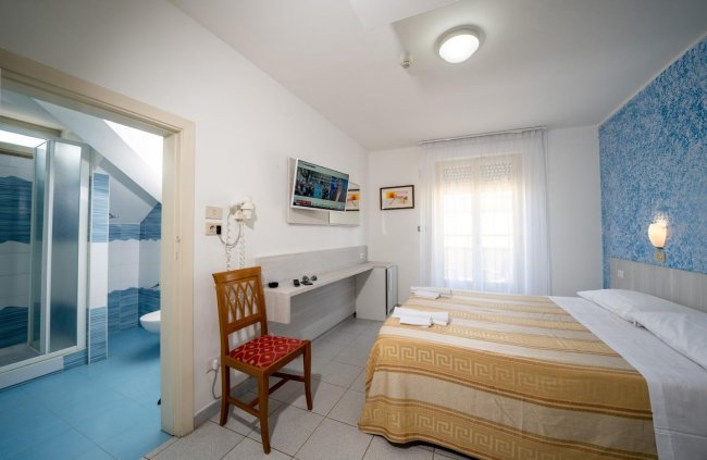 Camera da letto con bagno privato e TV a muro.