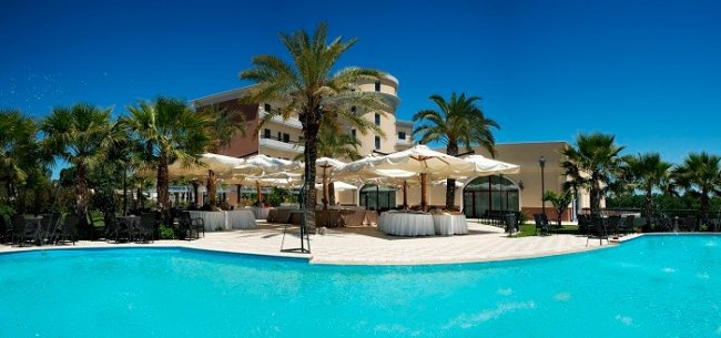 Piscina con palme e ombrelloni.