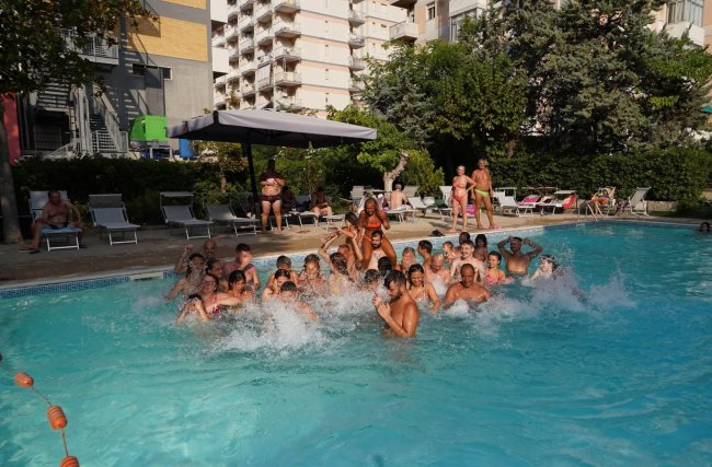 Persone che giocano in una piscina affollata.