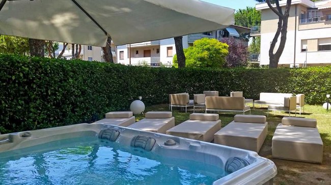 Vasca idromassaggio all'aperto con lettini e ombrellone.