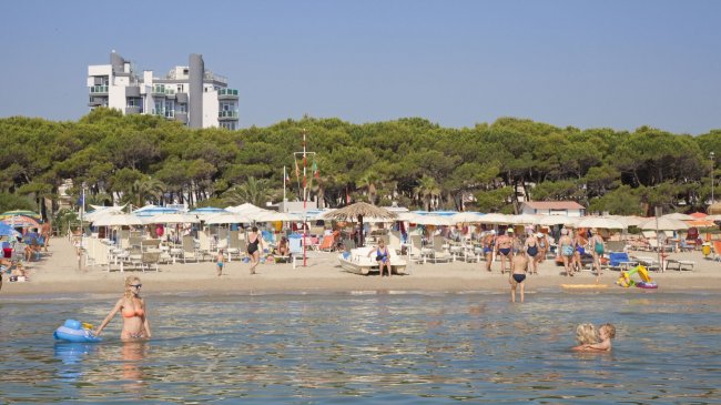 Spiaggia affollata con hotel sullo sfondo.