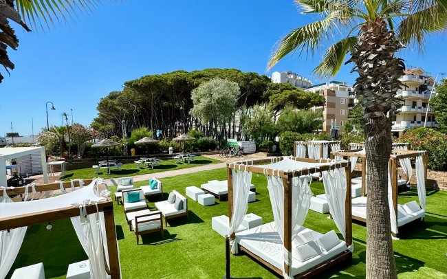 Giardino con letti a baldacchino e sedute su prato.