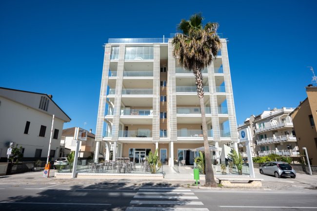 Edificio moderno con una palma davanti e cielo blu.