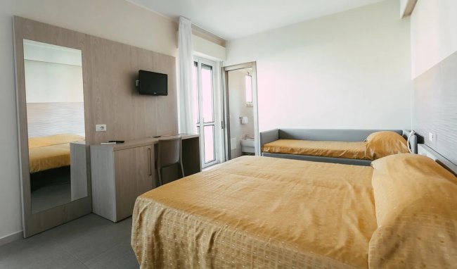 Camera d'albergo con due letti e un balcone.