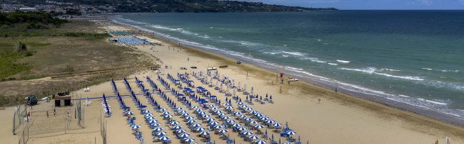 Spiaggia con ombrelloni blu e mare calmo.