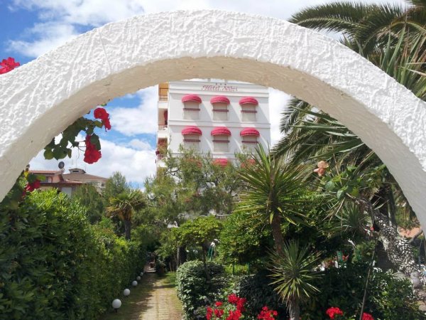 Arco bianco con vista su giardino e edificio.