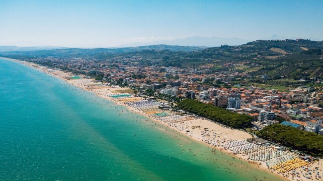 Spiaggia affollata vista dall'alto con mare turchese.