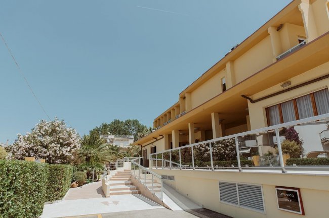 Edificio giallo con rampe e giardino.