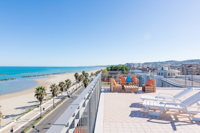 Terrazza con vista sul mare e sedie a sdraio.