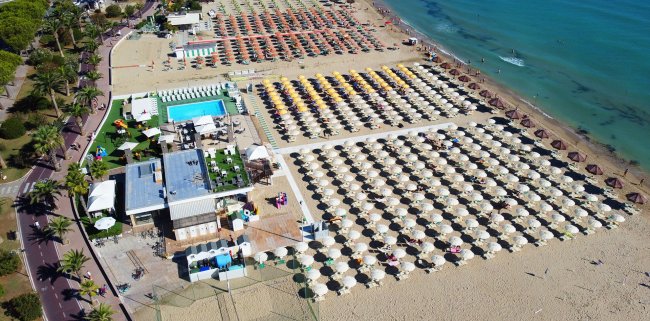 Spiaggia con file di ombrelloni colorati e mare.