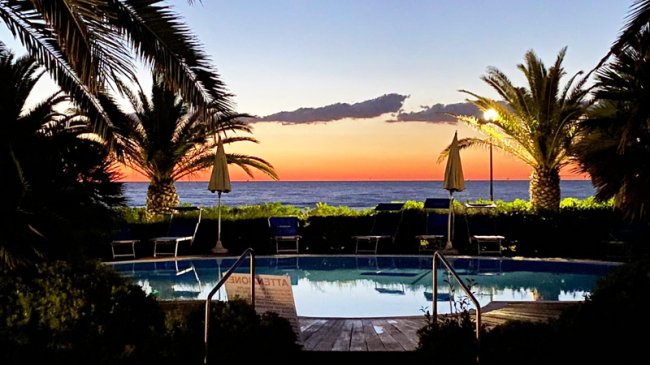 Piscina tra palme al tramonto.