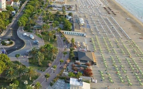 Spiaggia con ombrelloni verdi dall'alto.