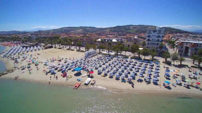 Vista aerea di una spiaggia affollata con ombrelloni.