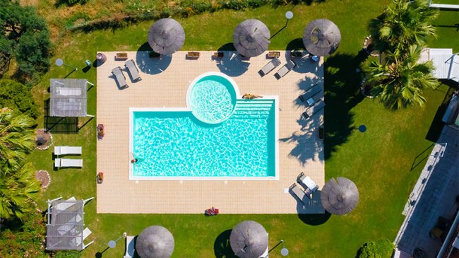 Piscina esterna con sdraio e ombrelloni.