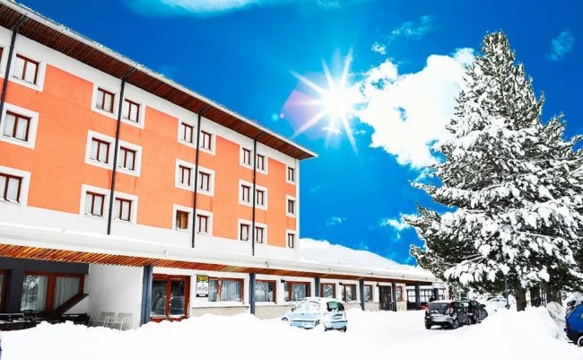 Edificio arancione in un paesaggio innevato e soleggiato.