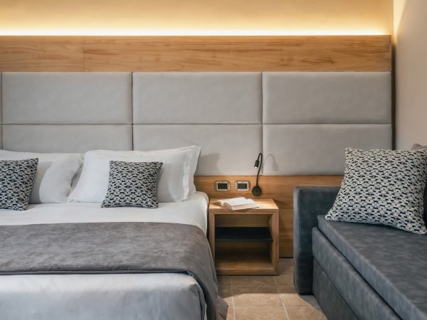 Letto matrimoniale moderno con cuscini decorativi.