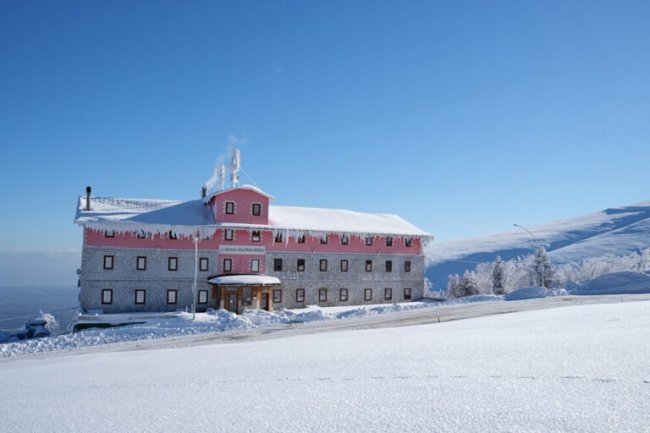 Edificio rosa coperto di neve sotto un cielo blu.