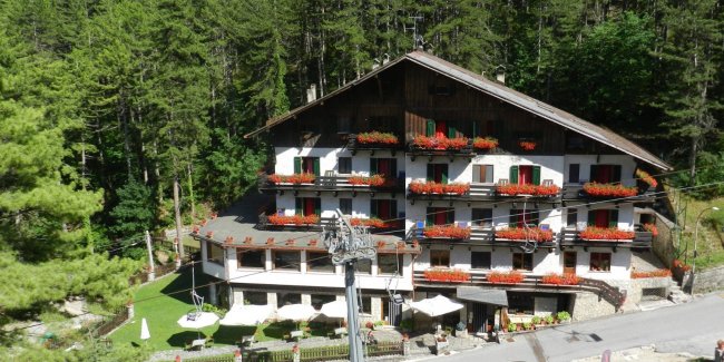 Hotel tra alberi con balconi fioriti.