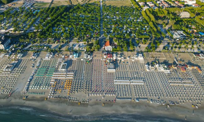 Veduta aerea di un litorale con file di ombrelloni e strutture balneari.