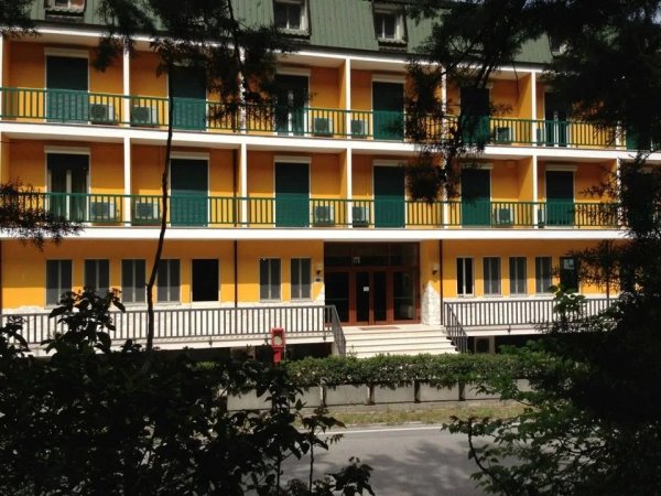 Edificio giallo con balconi verdi e porticato.