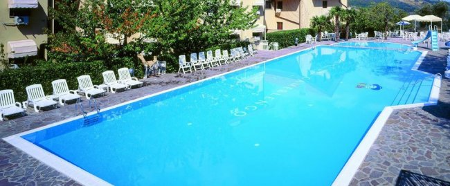 Piscina all'aperto con lettini bianchi.