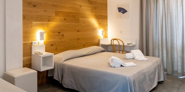 Camera con letto matrimoniale e parete in legno chiaro.