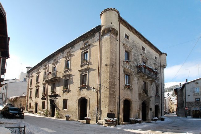 Edificio antico in pietra con balconi fioriti.